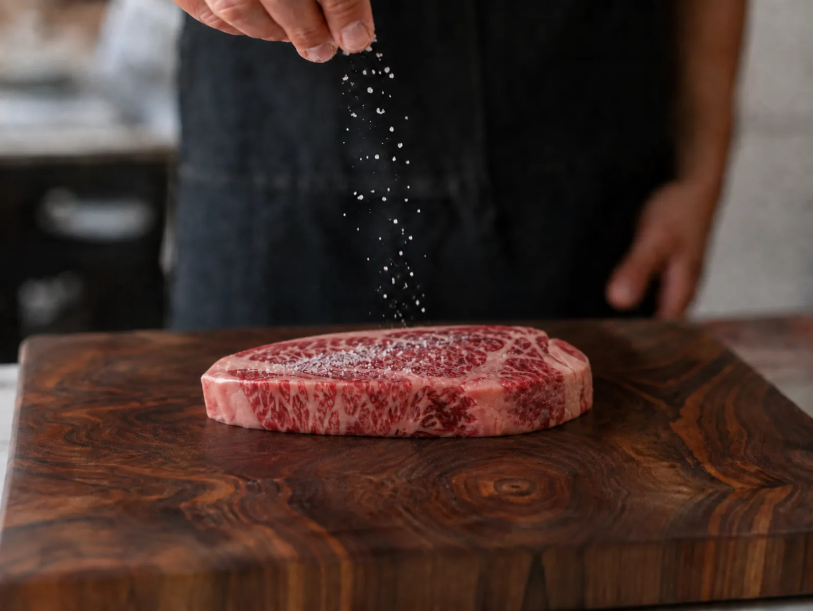 Một miếng ribeye Kangen Wagyu đang được ướp gia vị trên tấm gỗ óc chó